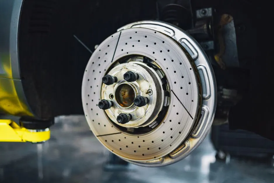 Mains gantées posant des plaquettes neuves sur un étrier de frein, voiture sur cric dans un garage